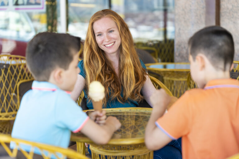 Happy summer nanny sitting outside with smiling kids, enjoying ice cream. Summer nanny jobs. How to find summer nanny jobs and when to start looking.